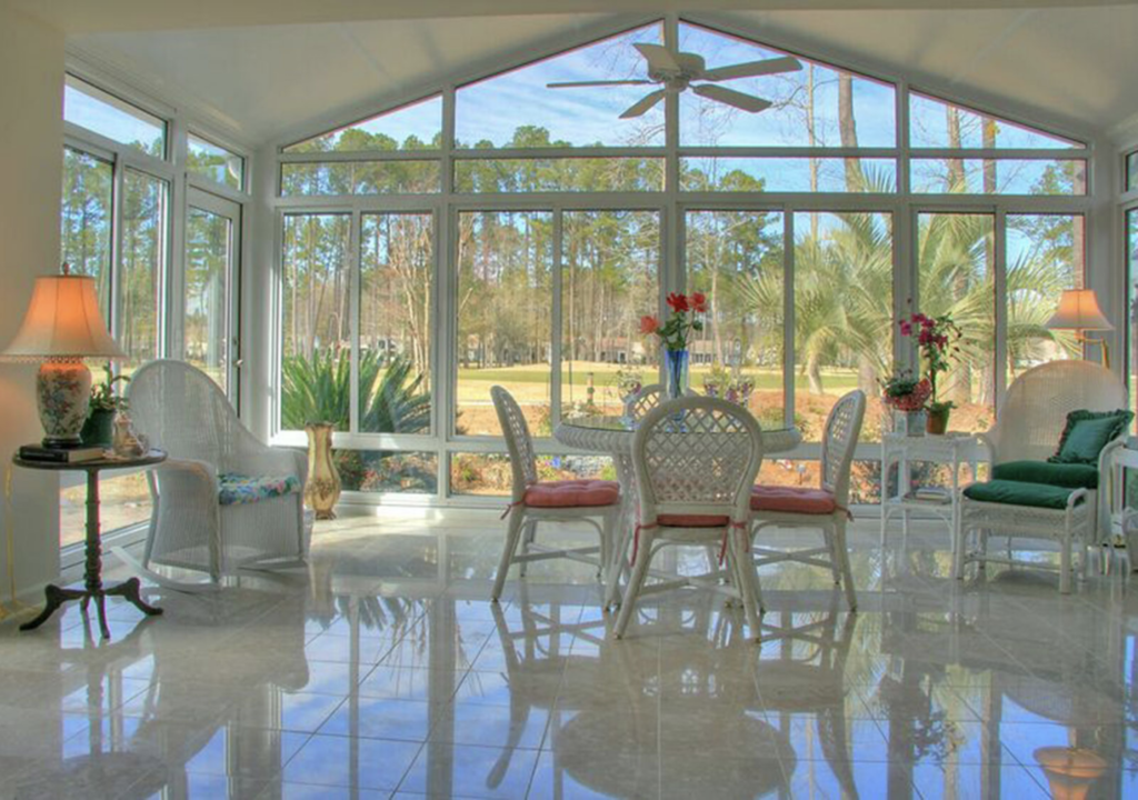 a photo depicting the interiorrof a sunroom showing a celiing fan and furniture