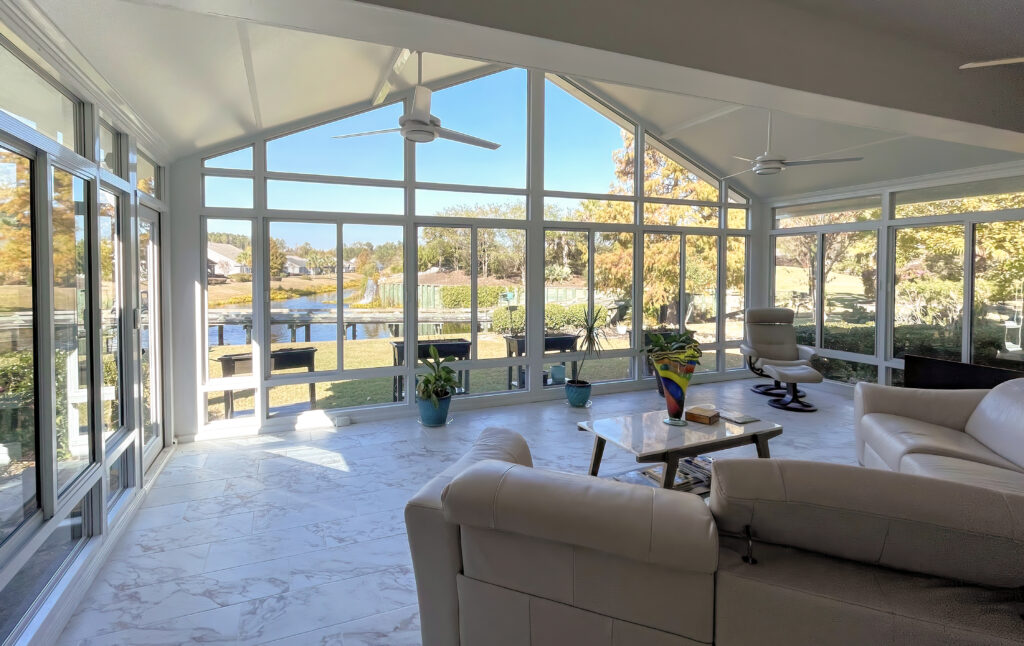 a photo depicting the interiorrof a sunroom showing a celiing fan and furniture