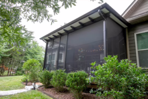 Screened porch addition with a wood-look ceiling, string lights, and railing attached to the back of a house